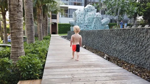 Two-year-old blond boy runs away on a wooden path. Stock Footage 104702545