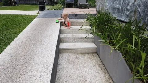 Two-year-old blond boy playing with a toy on the steps. Stock Footage 104702558