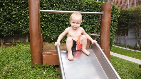 Two-year-old blond boy with great joy and fun down the hill on the Playground. Stock Footage 104848655