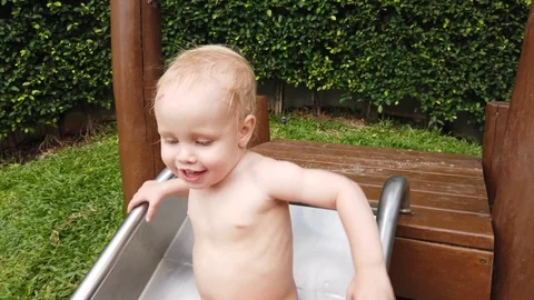 Two-year-old blond boy with great joy and fun down the hill on the Playground. Stock Footage 104848657