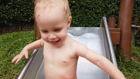 Two-year-old blond boy with great joy and fun down the hill on the Playground. Vidéo 104848731