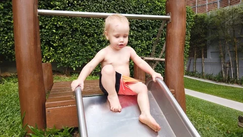 Two-year-old blond boy with great joy and fun down the hill on the Playground. Stock Footage 104848779