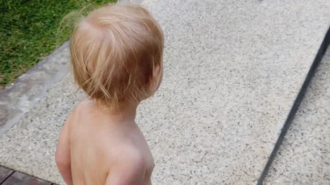 A two year old blond boy, with his back to the camera, the wind develops his hai Stock Footage 104849012