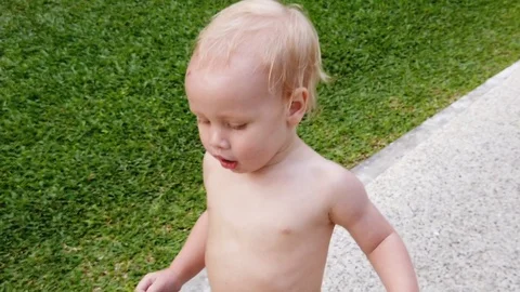 Two-year-old blond boy runs along the path, close-up, shakes plump cheeks Stock Footage 104849042