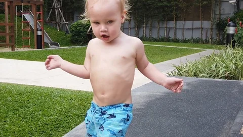 Two-year-old blond boy runs along the path, close-up, shakes plump cheeks Stock Footage 104849052