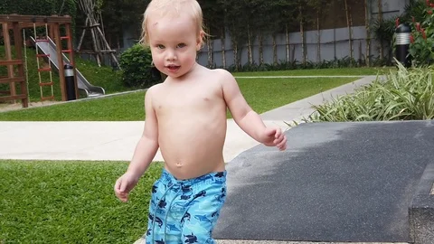 Two-year-old blond boy runs along the path, close-up, shakes plump cheeks Stock Footage 104849072