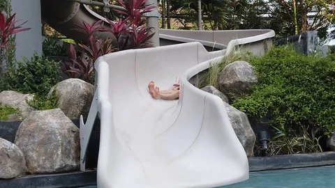  two-year-old blond boy with his father very fun down the water slide into the p Stock Footage 104849321