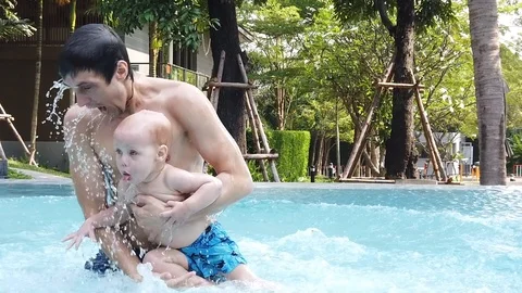 Two-year-old blond boy with his father splashing in the pool Stock Footage 104849356