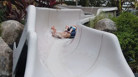  two-year-old blond boy with his father very fun down the water slide into the p Stock Footage 104849358