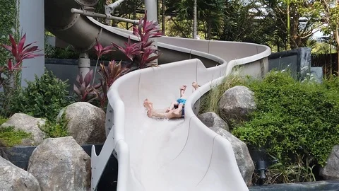  two-year-old blond boy with his father very fun down the water slide into the p Stock Footage 104849378