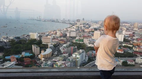 Two-year-old blond boy stands on the view platform and looks at the city. specie Stock Footage 104950171