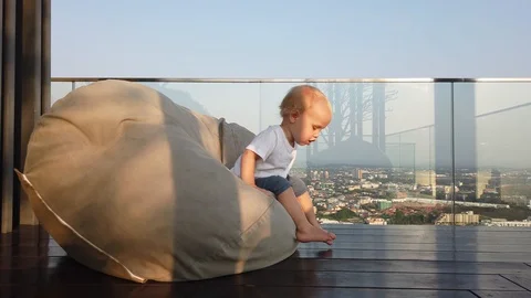 A two-year-old blond boy looks down at the city through the glass, Stock Footage 105052634