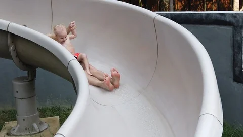 Two-year-old blond boy with his father fun down the water slide  Stock Footage 105053218