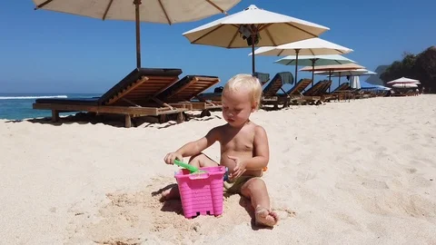 Two-year-old blond boy playing with sand on the beach.  Vidéo 108577878