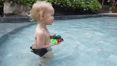 Two year old blond child playing with a toy while in the pool. Stock Footage 104702102