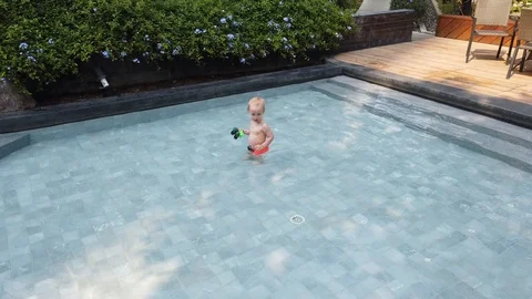 Two year old blond child playing with a toy while in the pool. Stock Footage 104702114