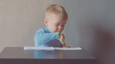 Two year old boy is drawing with marker at album and eating apples 스톡 동영상 108049901