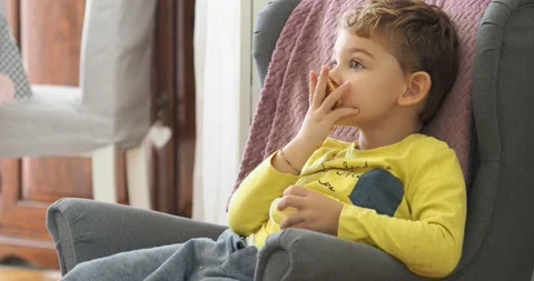 A two year old boy eats a cookie sitting on the sofa. Stock Footage 143114327
