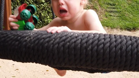  the two-year-old boy got scared and screamed, the child swung on the swing alon Stock Footage 104749733