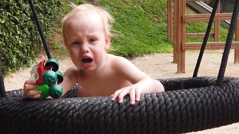  the two-year-old boy got scared and screamed, the child swung on the swing alon Stock Footage 104749751