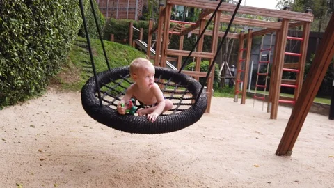 the two-year-old boy got scared and screamed, the child swung on the swing alon Stock Footage 104749809