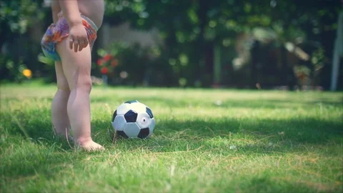 A two-year-old boy likes to play football in the park, run and kick the ball. Stock Footage 92892590