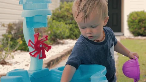 Two year old boy playing at water table. Tilt from hand to face.  Stock Footage 129896309