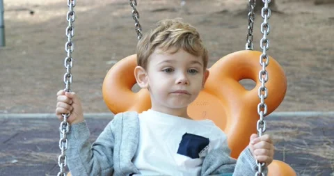 A two year old boy relaxes by swinging in a park. Stock Footage 143113751