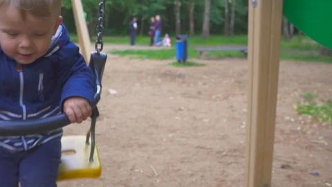 Two year old boy is riding on a swing in the park Видео 96667747