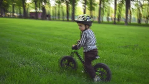 Two year old boy riding a runbike in a park. View from the back Video stock 130201641