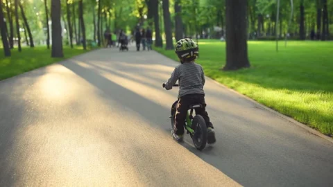 Two year old boy riding a runbike in a park. Backview. Video stock 130204228