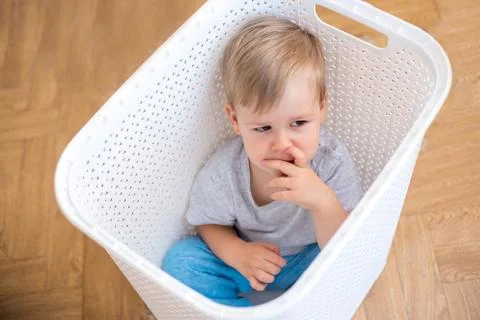 Two year old boy sitting in a laundry basket Stock Photos