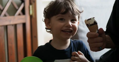 A two-year-old boy smiles happily as he starts eating ice cream. Stock Footage 143113037
