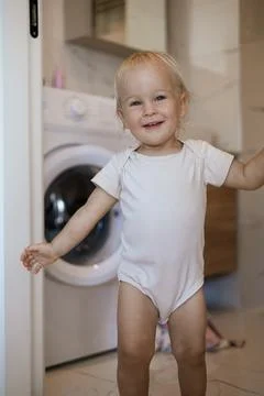 Two year old child doing household chores. Loading washing machine. Stock Photos