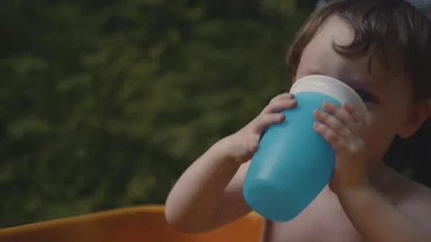 Two year old child drinking water from a beaker Stock Footage 168980420