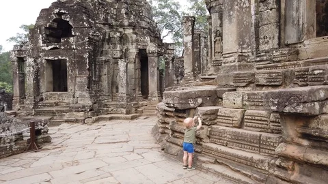 Two-year-old child examines the walls of the temple Bayon, Angkor Wat, Cambodia. Stock Footage 105984477