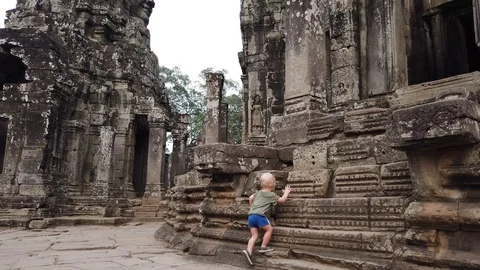 Two-year-old child examines the walls of the temple Bayon, Angkor Wat, Cambodia. Stock Footage 105984609