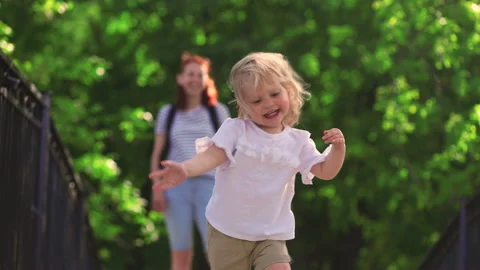 A two-year-old child runs in the park, runs to meet his parents Stock Footage 154409974