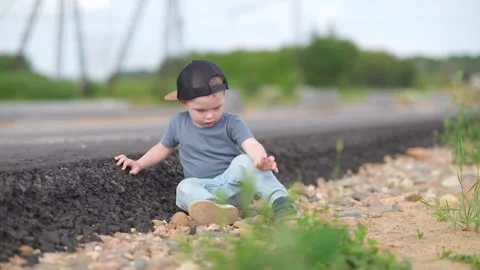 A two-year-old child is sitting alone on the side of the highway. A child on the Stock Footage 245656059