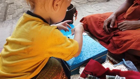 A two-year-old child tries to shove a bill into a donation box Stock Footage 106827926