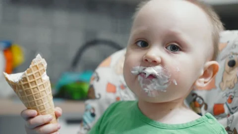 Two year old chubby child eats ice cream in the kitchen Stock Footage 279395746