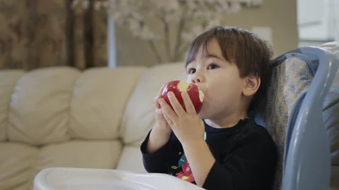 Two-year-old kid eats a big red apple Stock Footage 249685524