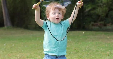 Two year old making giant bubbles close up smile Stock Footage 72631689