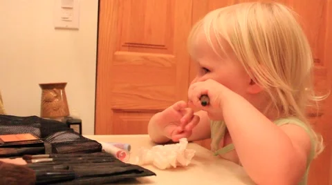 Two year old slowly and roughly applies cheek color Stock Footage 41651861