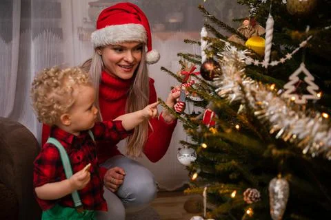 A two-year-old son points his finger at his mom's Christmas tree. Foto stock
