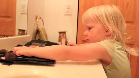 Two year old studiously switches makeup brushes Video stock 41651708