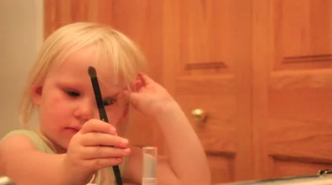 Two year old switches eye shadow brush Stock Footage 41651693