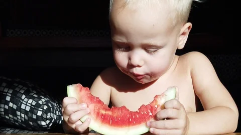 Two-year-old white-haired boy funny eating watermelon Stock Footage 110945618