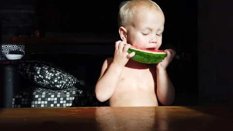 Two-year-old white-haired boy funny eating watermelon Stock Footage 110946202