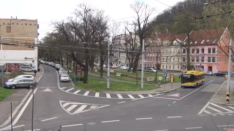 Two yellow and blue trolleybuses meet at crossroads with a boulevard Stock Footage 64694832